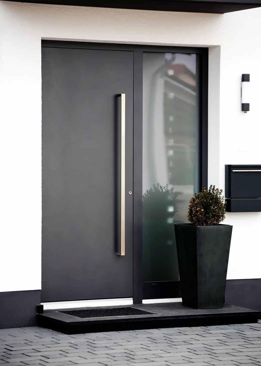 Graue Aluminiumtür mit Blumentopf von außen